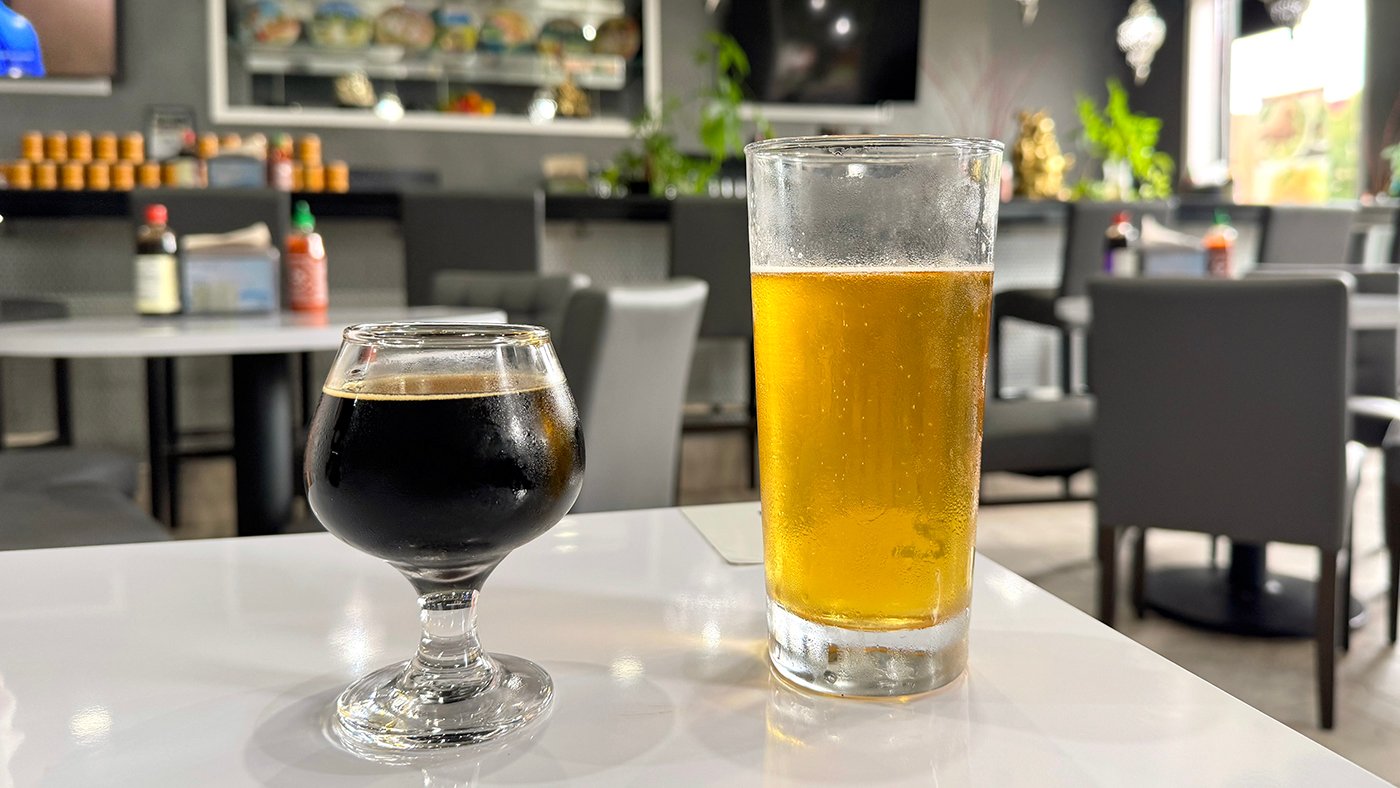A small dark beer and larger pale ale on a table