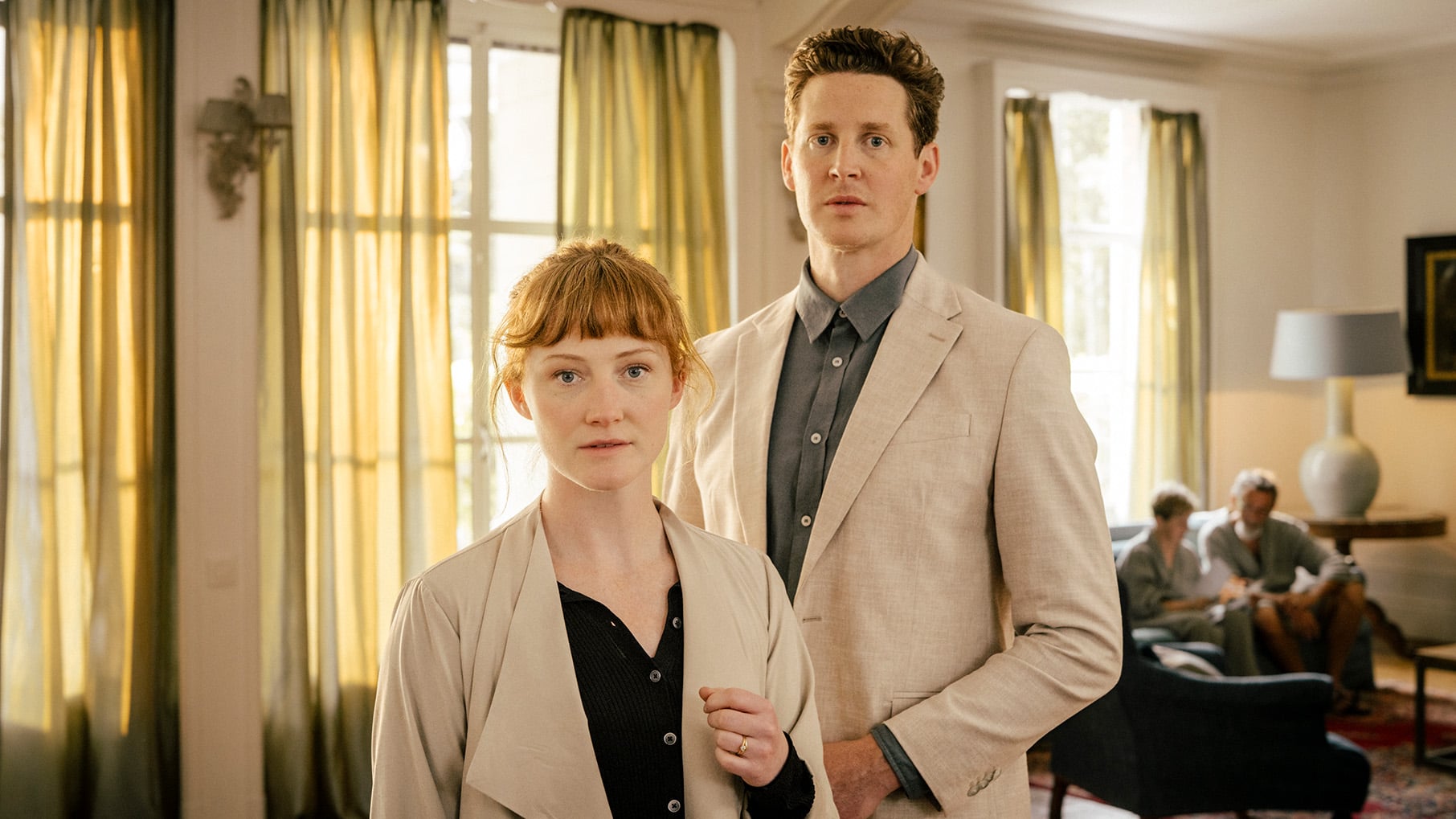 Naomi looks at the camera with Finley standing behind her and two people sitting in the background