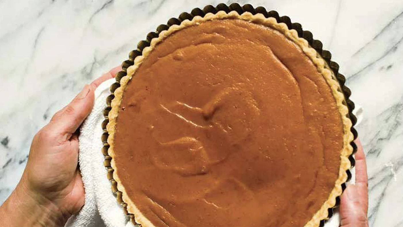 Two hands holding a pumpkin tart
