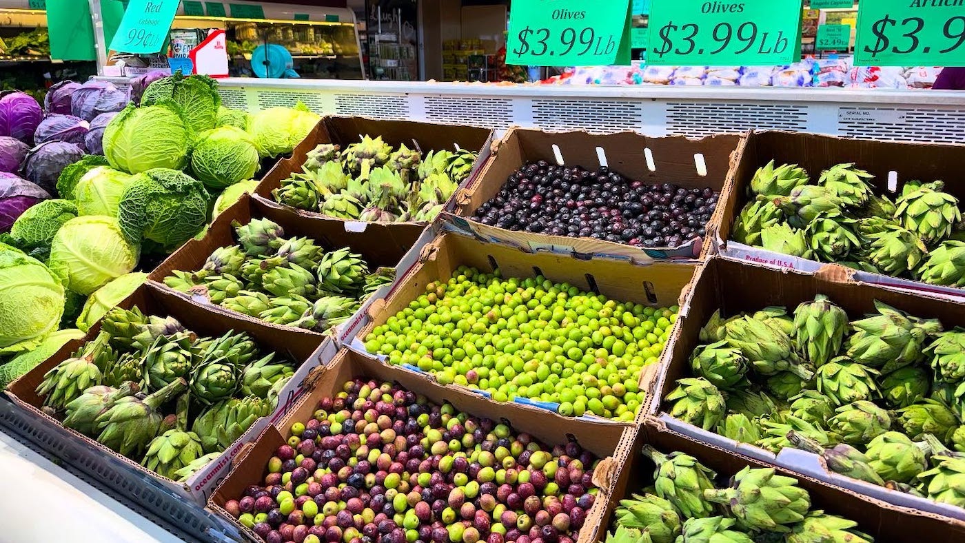 Produce such as olives, artichokes, and cabbage on display in a grocery store