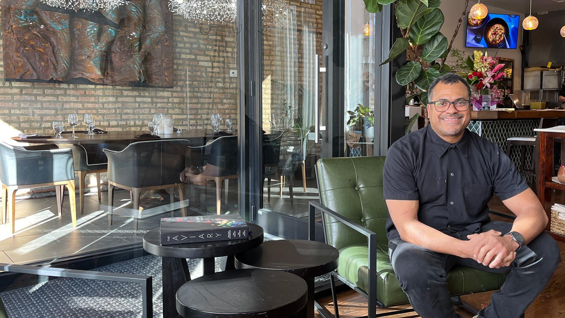 Mychael Bonner smiles in a chair in his restaurant