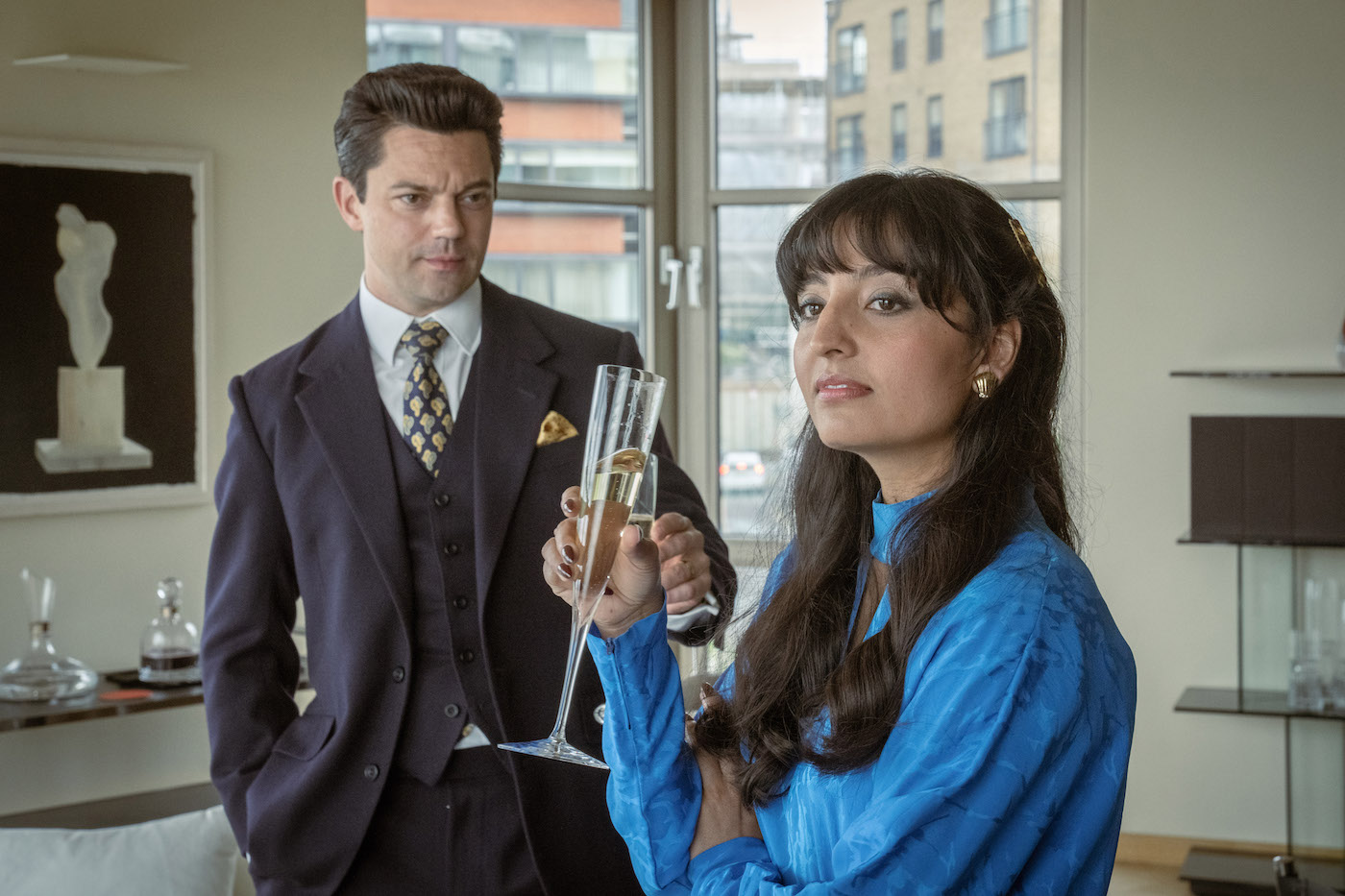 A woman holds a champagne flute in front of a man in a suit