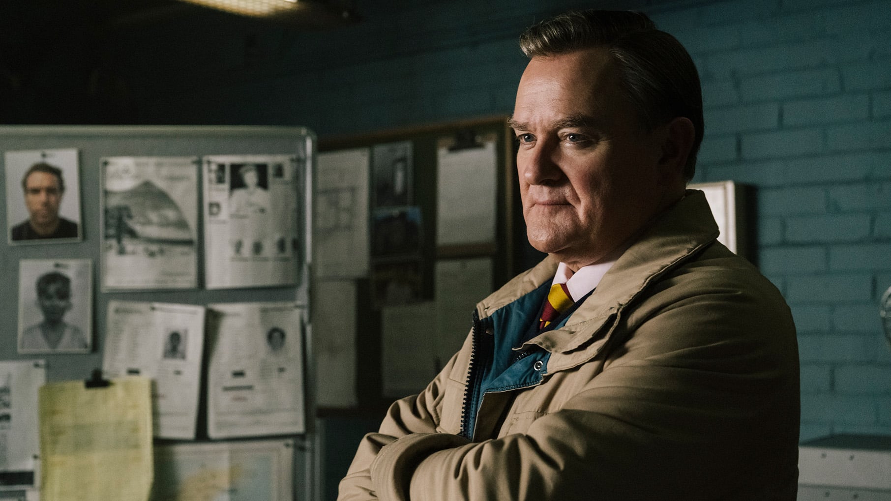 Boyce stands in an office with his arms crossed