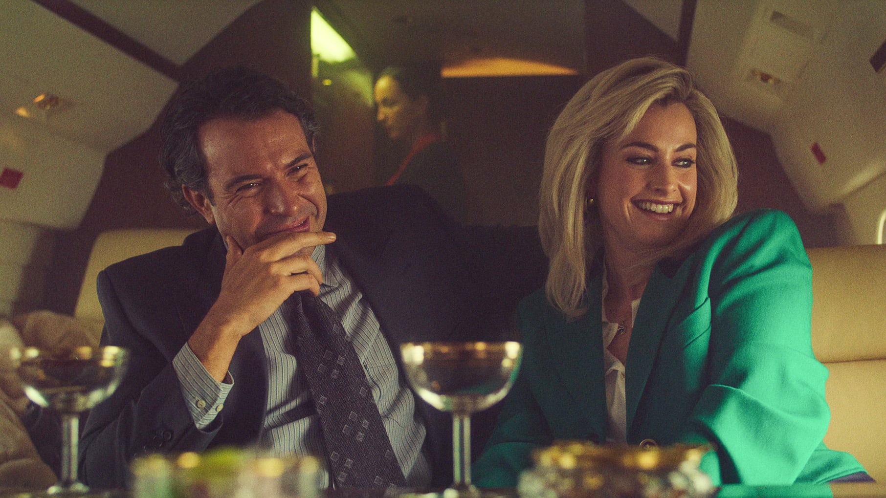John and Marnie Palmer laugh on a plane with martinis in front of them