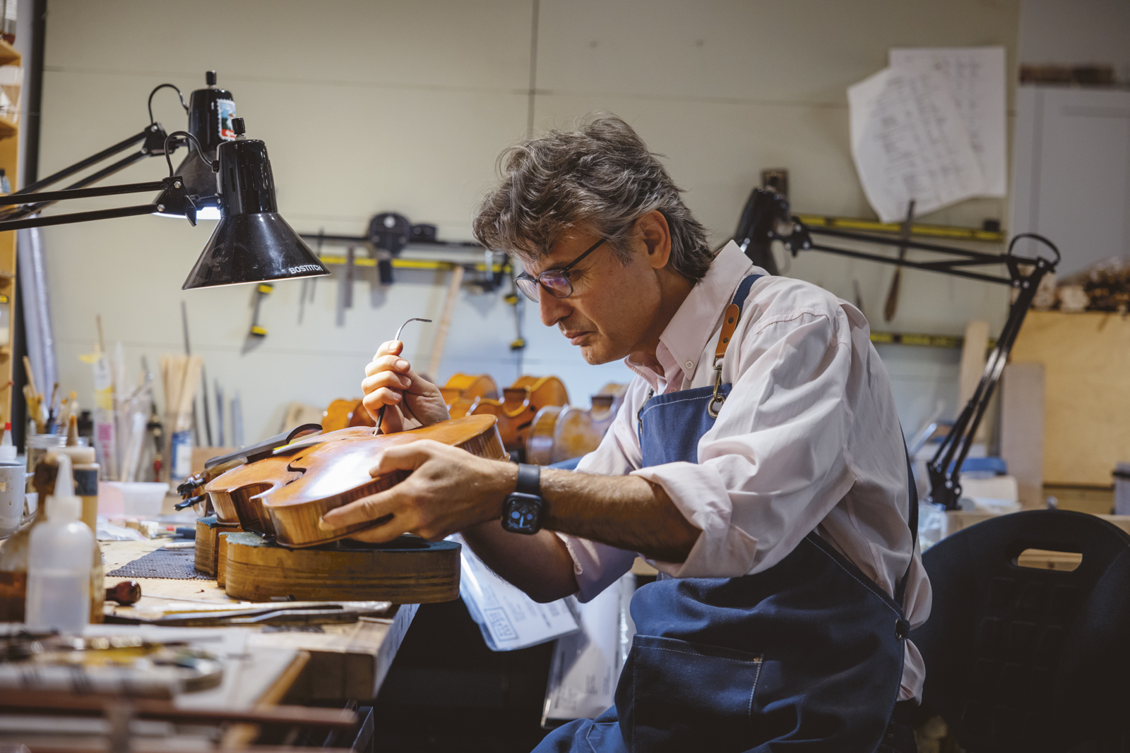 A man at a workbench makes a viola