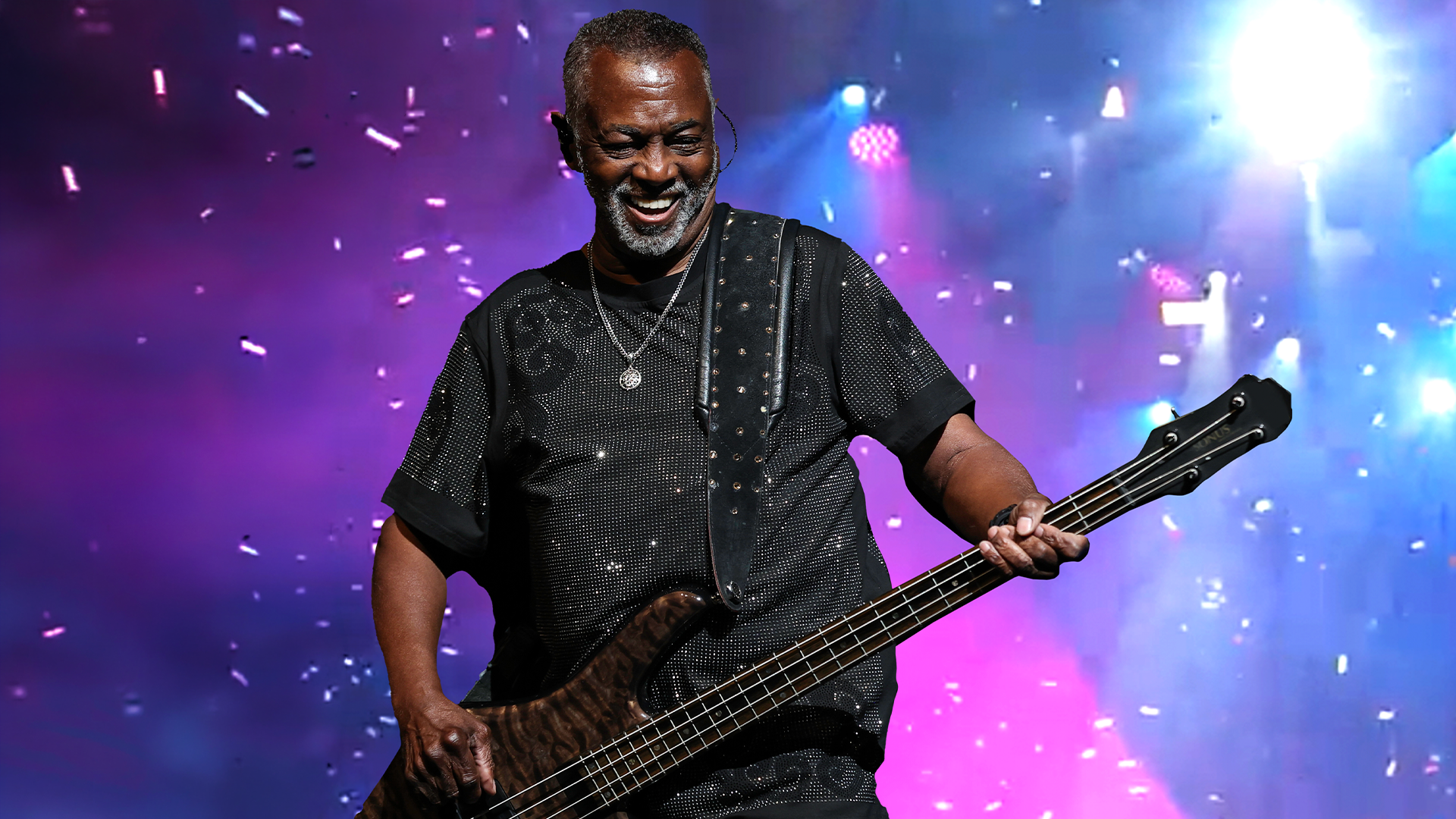 A man smiles while playing guitar on stage