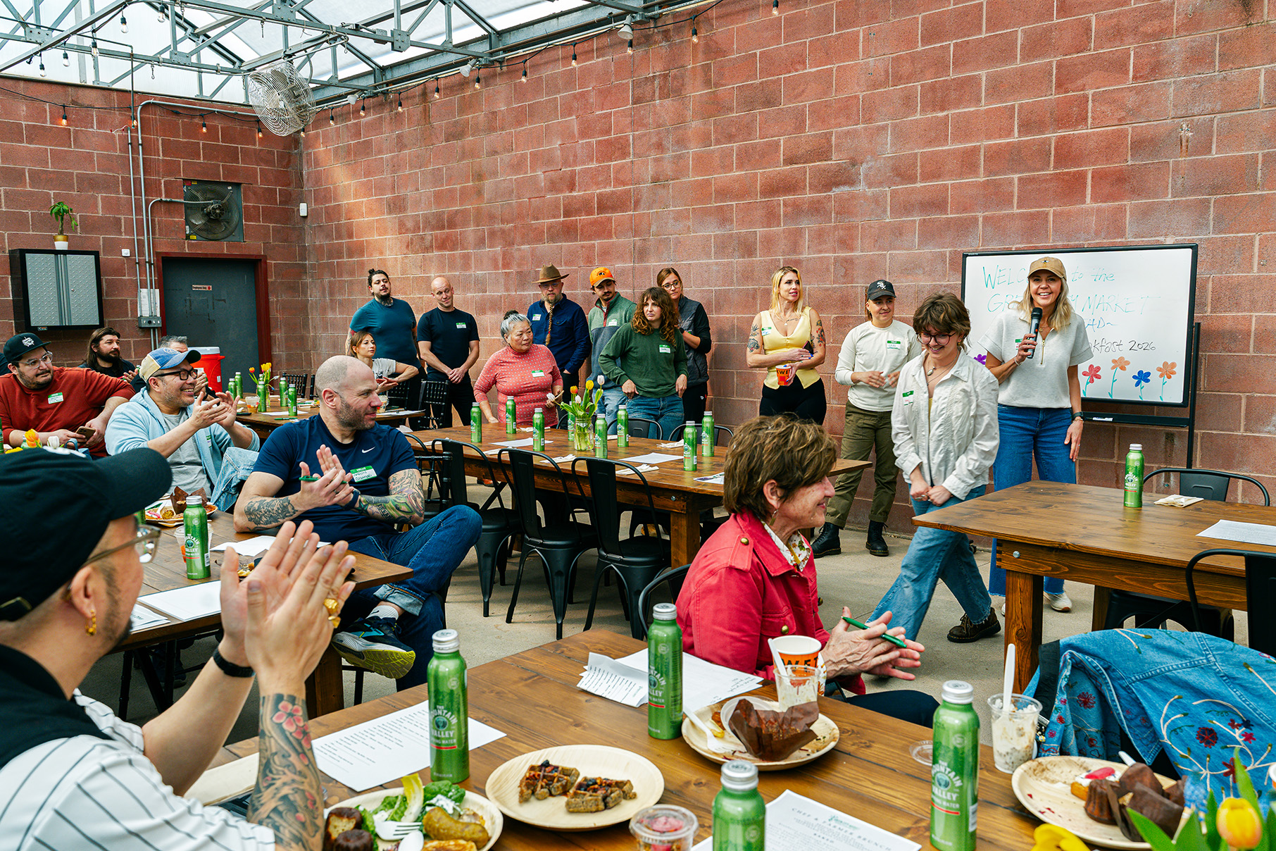 A line of people stands while others sitting at tables look at them