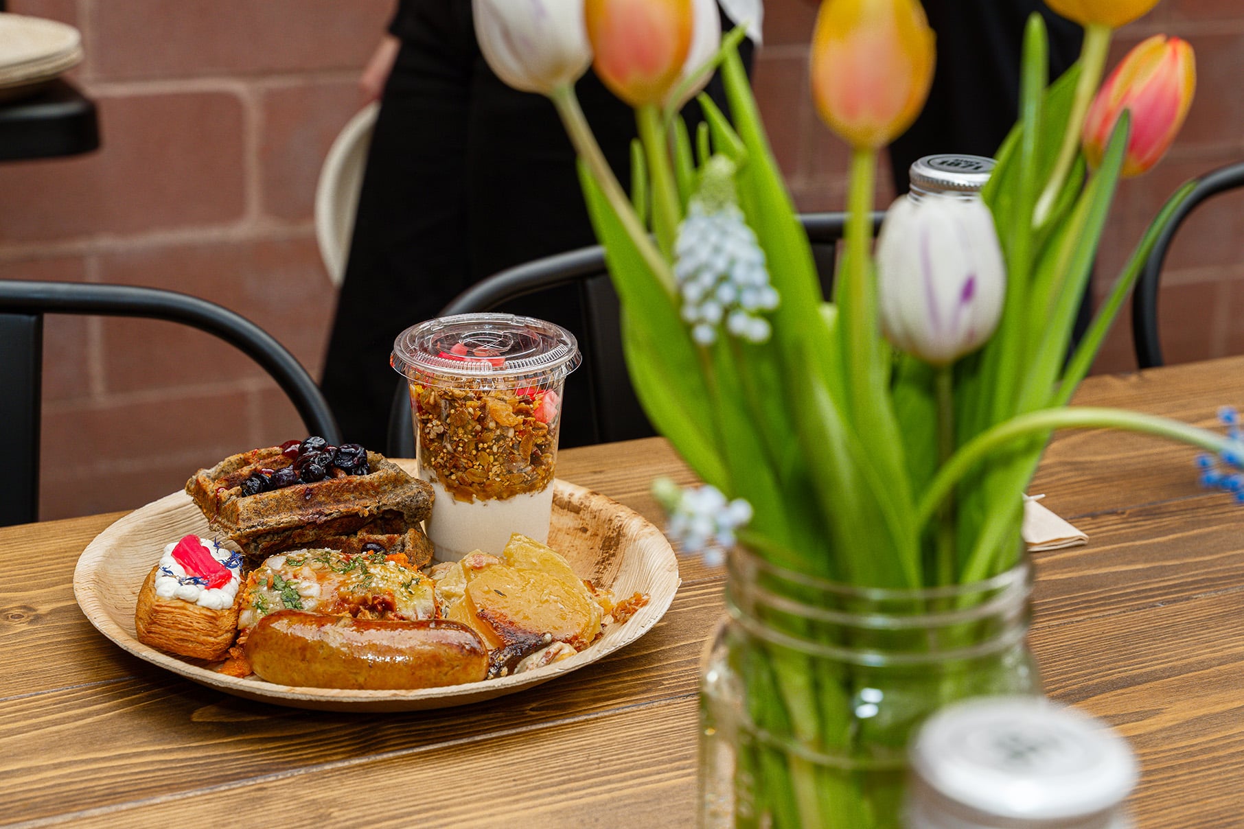 A plate of food on a table next to a vase with tulips