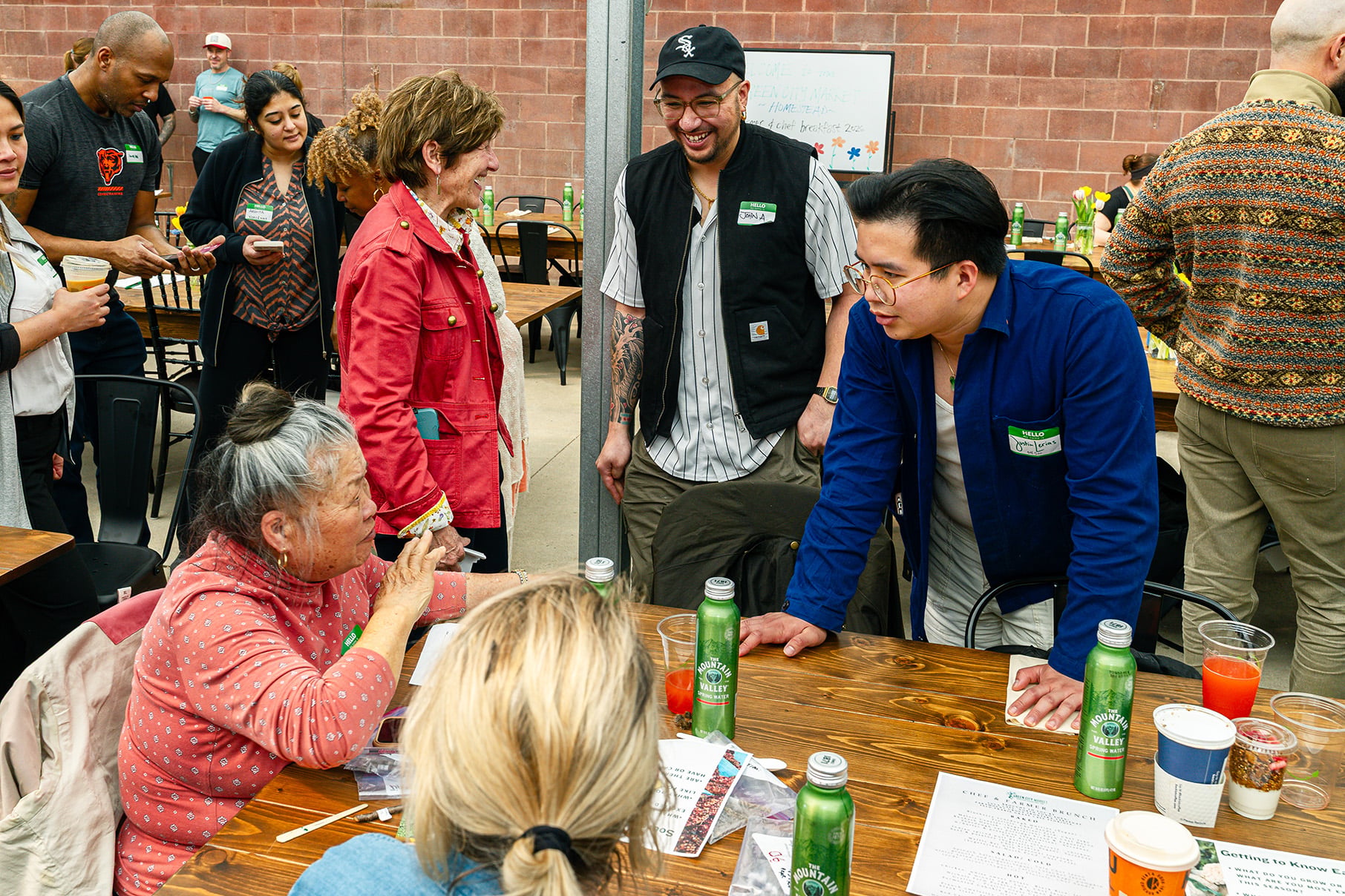 People converse, some sitting at a table and some standing