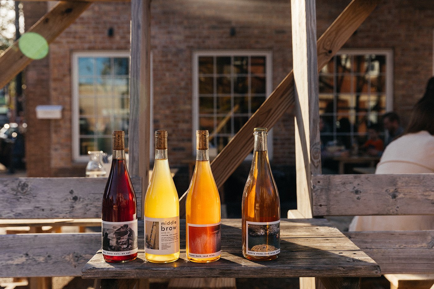 Four bottles of wine on an outdoor table in a sunbeam