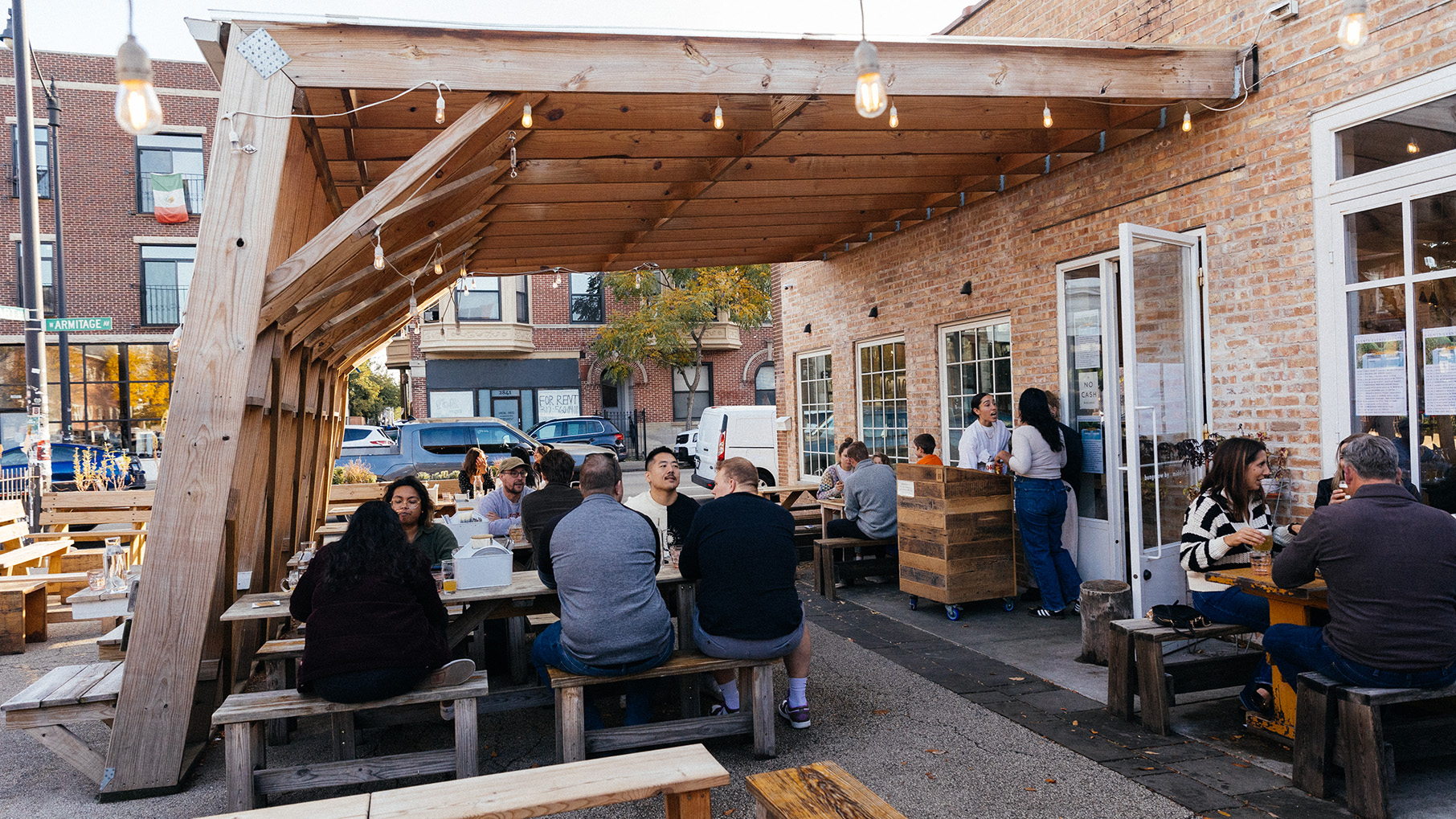 A covered patio with people dining at picnic tables
