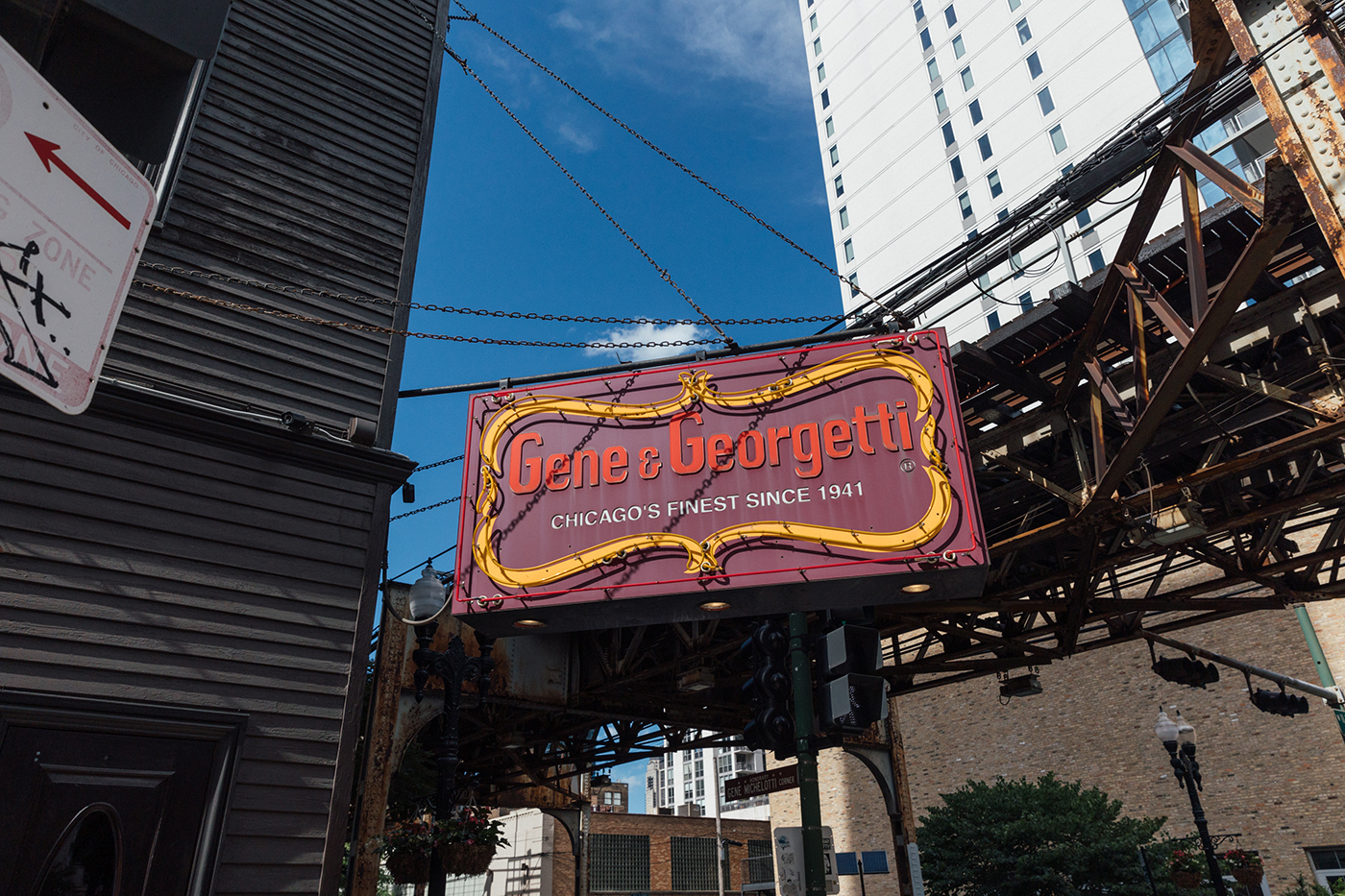 The sign of Gene & Georgetti in front of train tracks and a blue sky