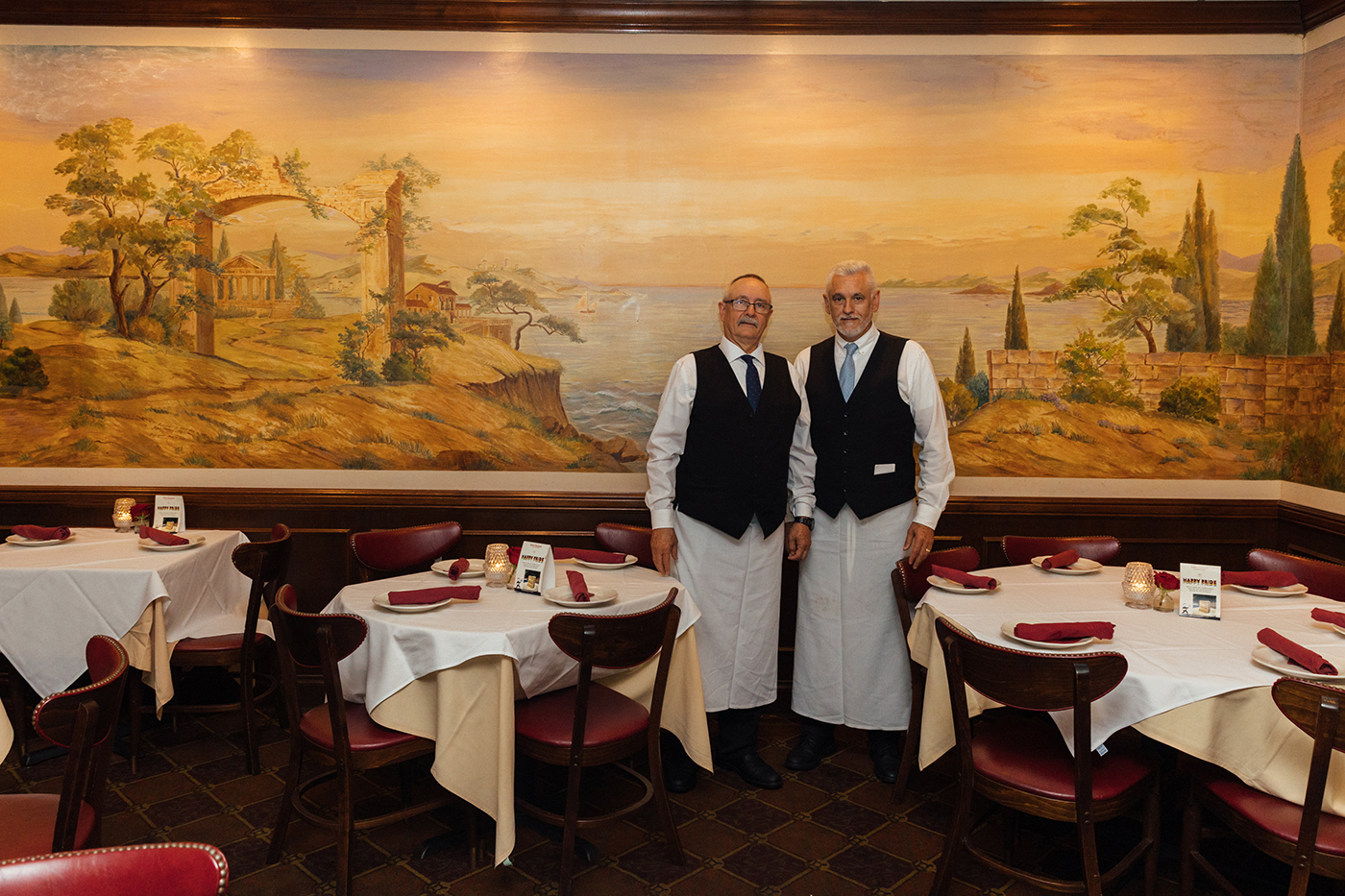 The Muñoz brothers pose in front of a mural amongst restaurant tables