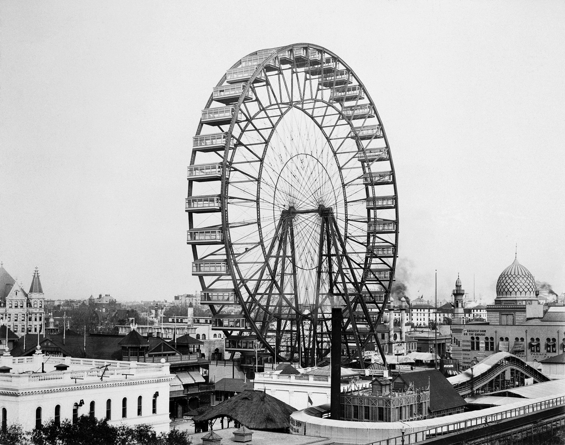 A black and white image of the Ferris Wheel at the World's Fair of 1893 in Chicago over some of the other buildings