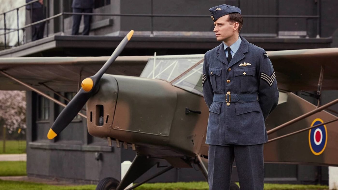 James stands in front of a plane in his military uniform