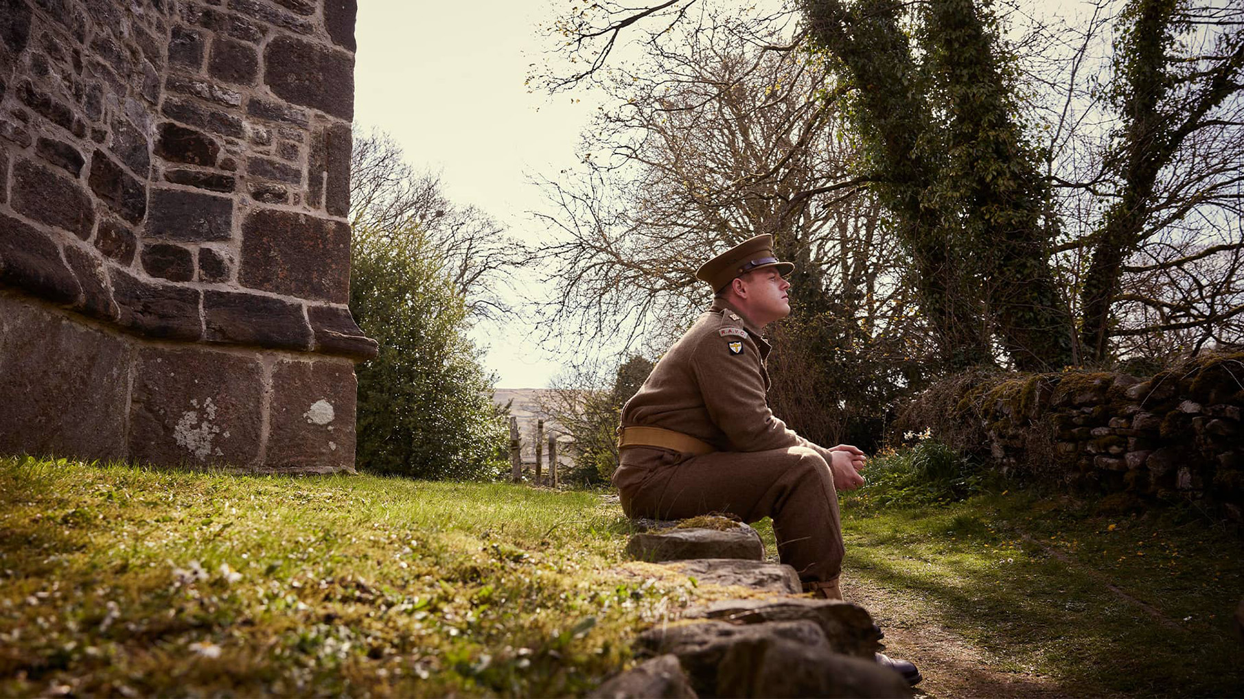 Tristan sits next to a path in his military uniform