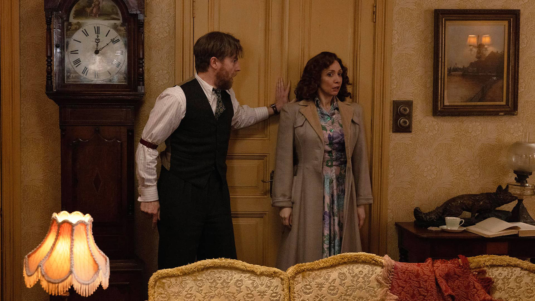Siegfried holds a door shut next to a woman who looks frightened