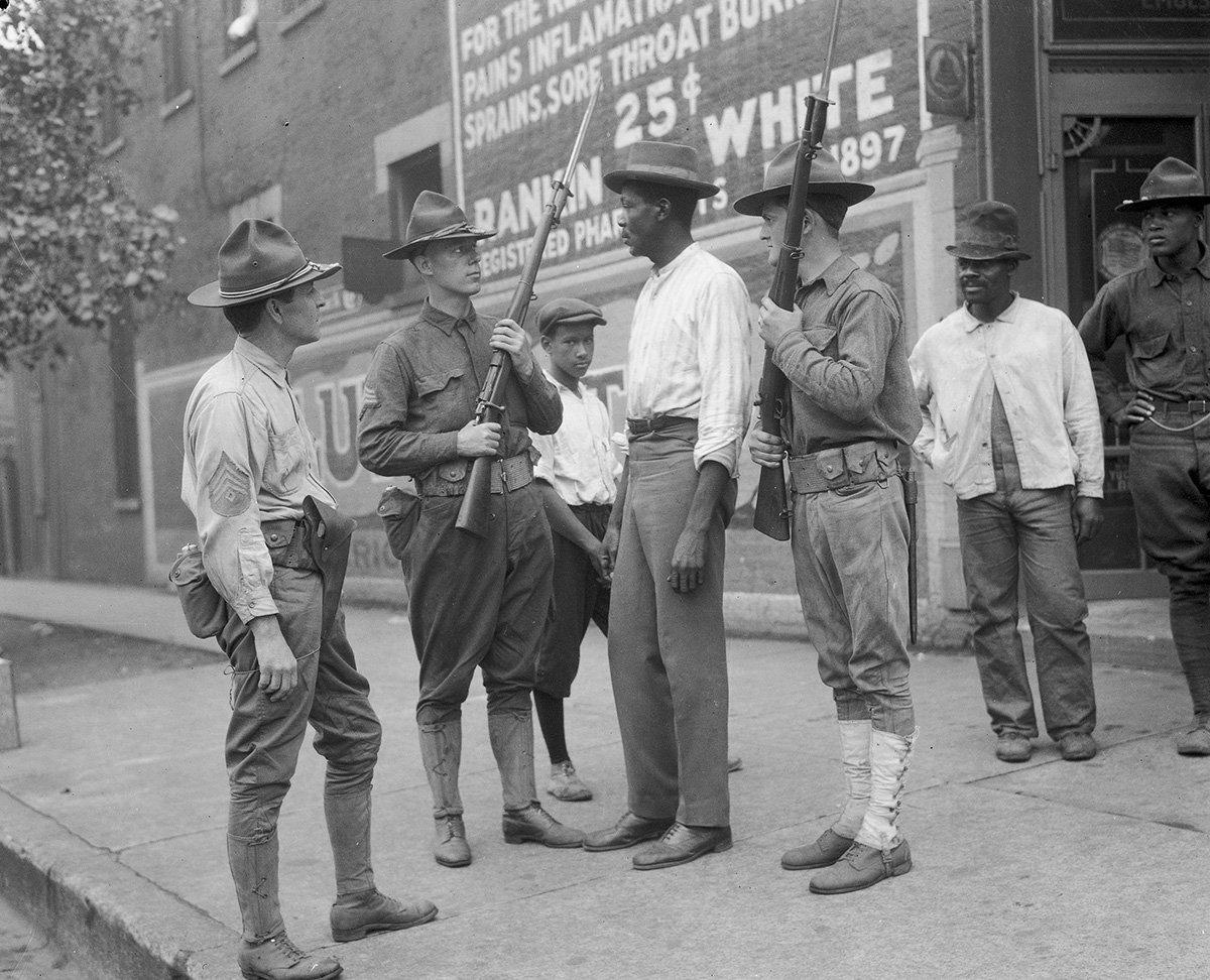 Illinois National Guard soldiers questioning a tall black man