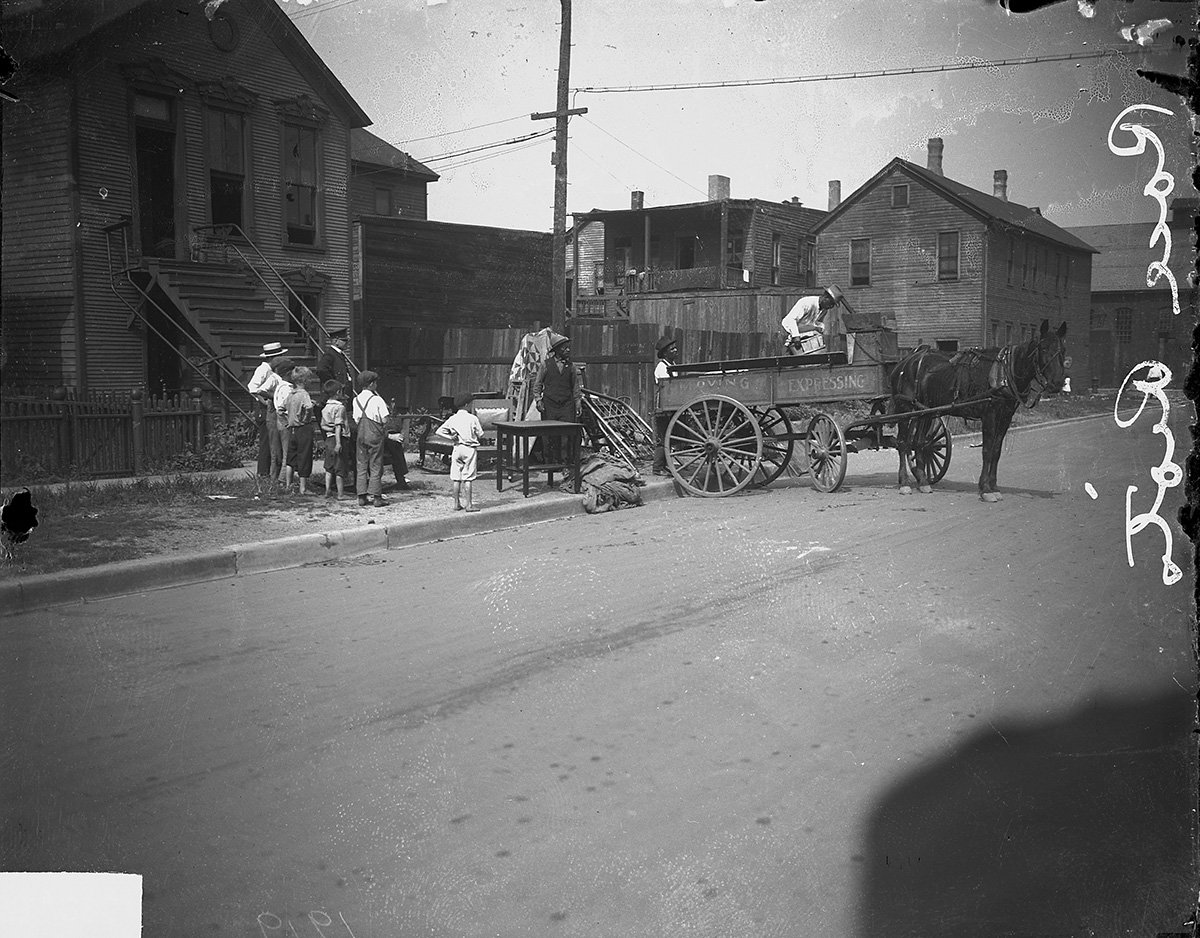 Three African-American men moving furniture while young Caucasian boys watch