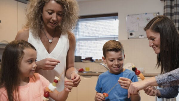 Family making fruit kebabs.