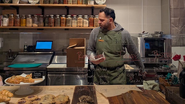 Mutaz Abdullah takes Middle Eastern flavors and desserts and makes "them into something a little more familiar to the American eye" at Seedo's Levantine Bakery, he says. Credit: Lisa Futterman for WTTW A man stands behind a bakery counter with pastries