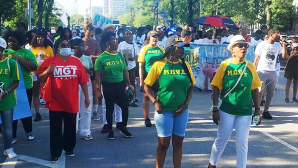 Credit: Chicago Survivors A group of people mostly wearing green and yellow shirts march down a city street