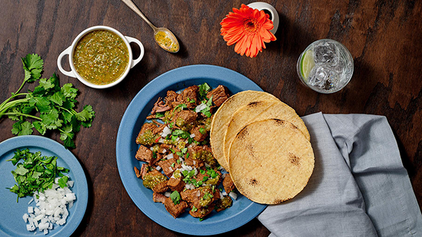 Tacos de Suadero con Salsa Verde con Chiles Mixtos. Credit: Pati's Mexican Table An overhead view of a table with brisket, tortillas, salsa, cilantro, onion, and more