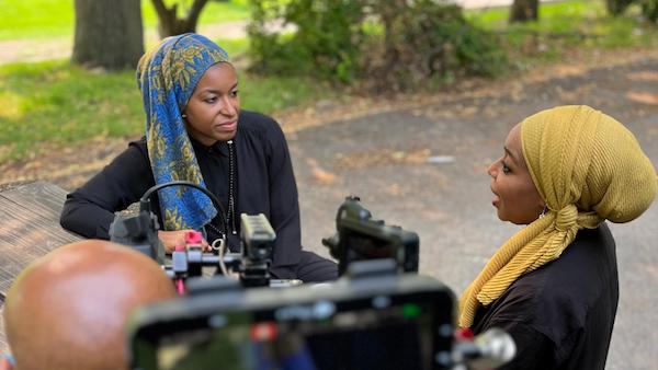 Alia Bilal, Chief Executive Director, Inner-City Muslim Action Network (IMAN), who will take part in a WTTW screening of 'American Muslims,' talks to her sister Malika Bilal, a host of the series. Credit: Timestamp Media Two women in headscarves talk to each other outside on camera