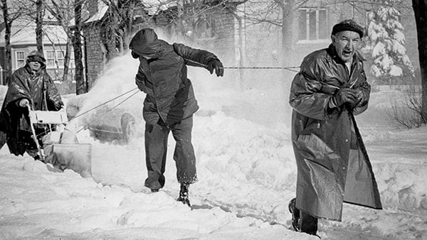 Black and white photo of men shoveling and blowing snow
