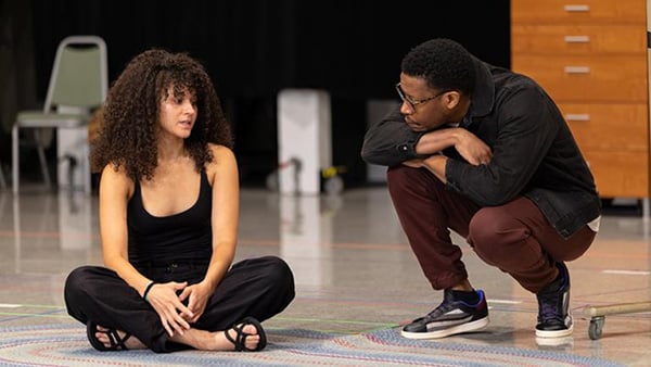 During a rehearsal, a woman sits cross-legged on a stage at the Steppenwolf, while a man crouches down beside her