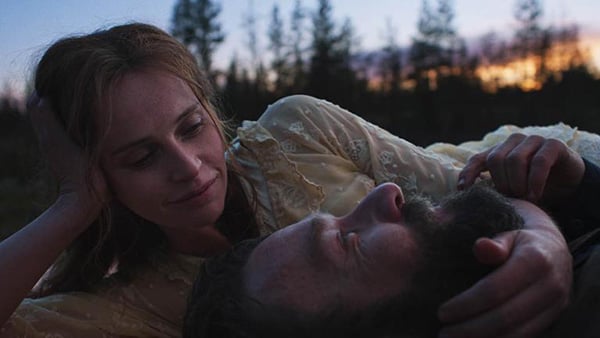 Felicity Jones and Joel Edgerton in 'Train Dreams.' (Adolpho Veloso/Courtesy of Sundance Institute) Felicity Jones wraps her arm around Joel Edgerton's head while lying in the grass in 'Train Dreams.'