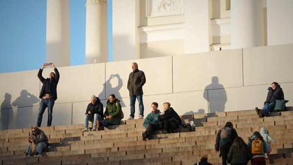 People enjoy the sunny weather with the Helsinki Cathedral of the background in Helsinki, Finland, Friday, Nov. 14, 2025. (AP Photo / Sergei Grits)