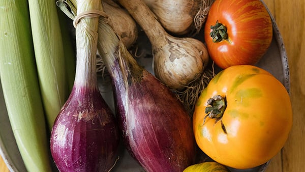 Onions, garlic, tomatoes, and baby corn on a plate on a table