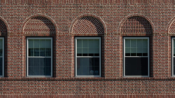 Three windows in a textured brick wall