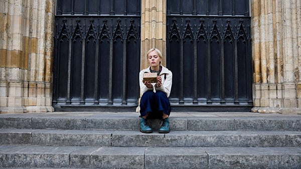 Patience sits on the steps of a church looking at a box