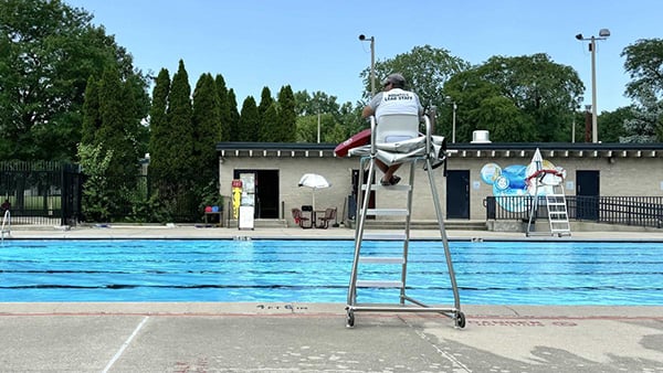 A lifeguard sits above an empty outdoor pool