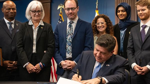Gov. JB Pritzker signs the Artificial Intelligence Safety Measures Act into law in Chicago on July 6, 2026, surrounded by lawmakers and advocates. (Maggie Dougherty / Capitol News Illinois)