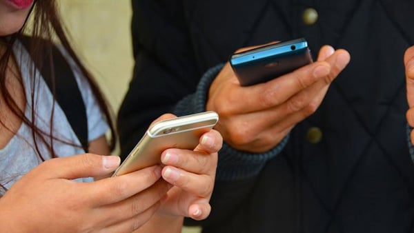A stock image of teens holding cell phones in their hands