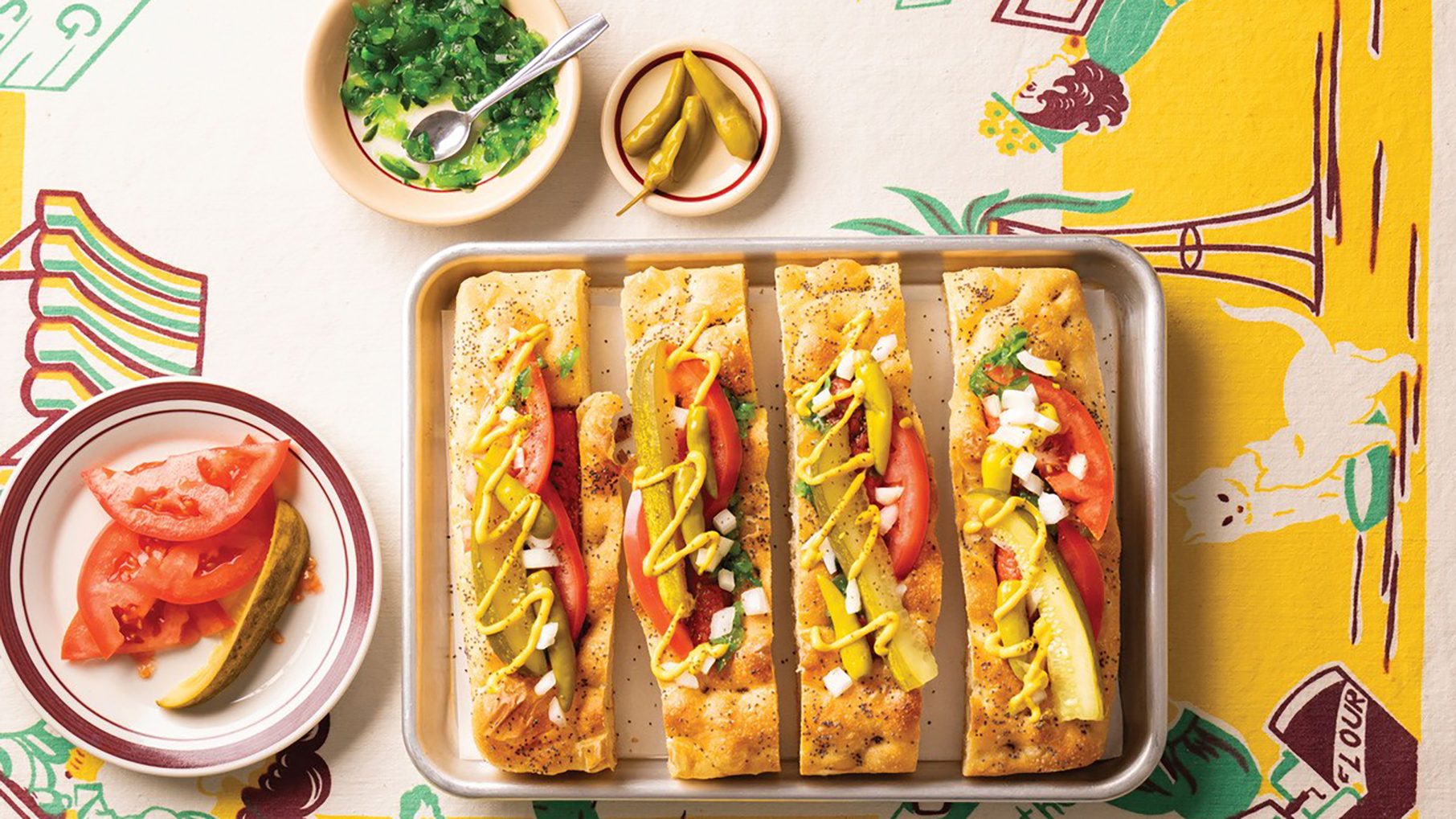 Chicago Dog Focaccia on a baking sheet, surrounded by the "dragged through the garden" ingredients
