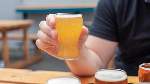 A person holds up a hazy beer