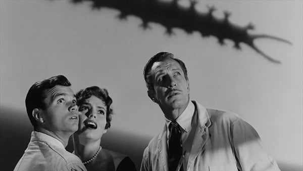 Three people look up at a tentacle-like thing in fright, in black and white