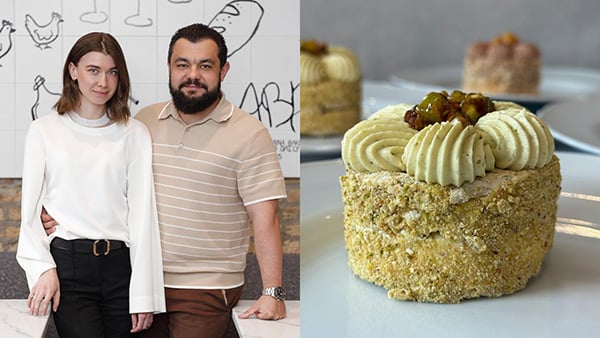 Iryna and Artur Yuzivik pose in their restaurant, next to a photo of a pistachio Kyiv cake