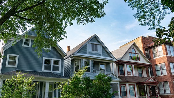 A row of houses seen through trees next to a brick multi-unit building