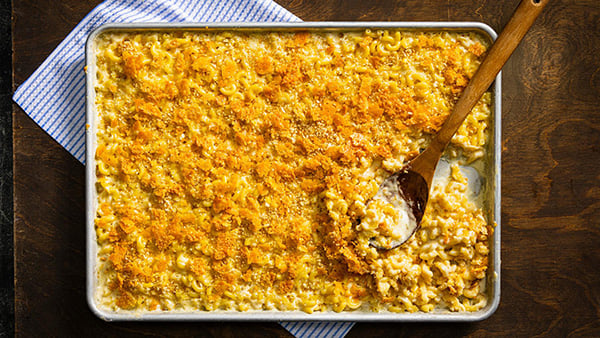 A sheet pan of mac 'n' cheese with a wooden spoon in it