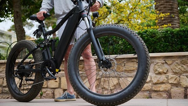 A person stands behind an e-bike 