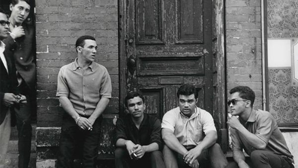 A black and white photo from 1971 picturing six men standing or sitting near a doorway stoop on a sidewalk
