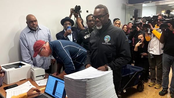 Mayor Brandon Johnson delivers a tall stack of papers to file for re-election
