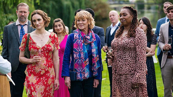 Judith, Suzie, and Becks stand on a lawn with other people