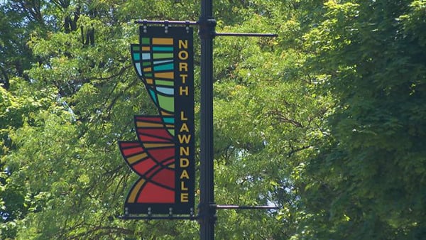 A colorful, geometric lamp post banner reading North Lawndale
