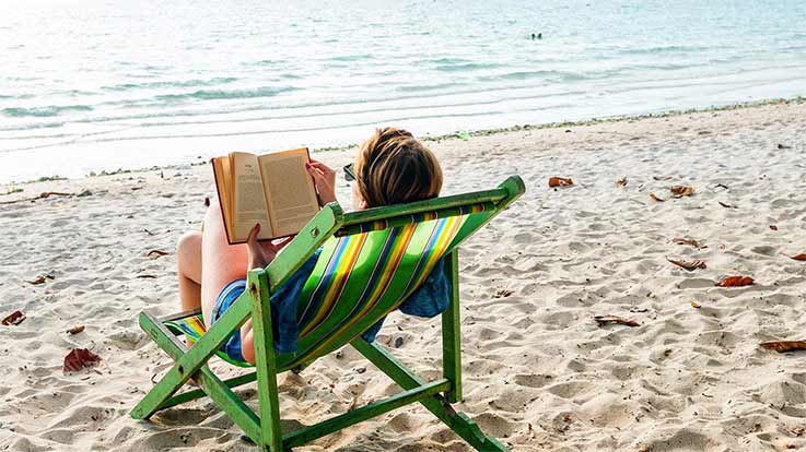 Person reading a book on the beach